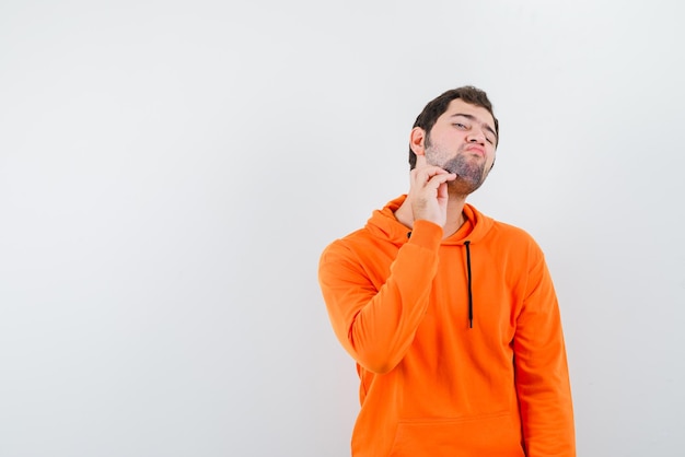 The young man is straching his chin on white background