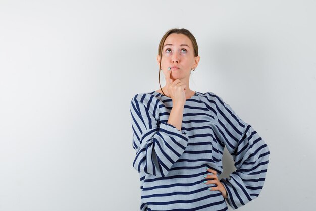 The young man is thinking by putting her forefinger on chin on white background