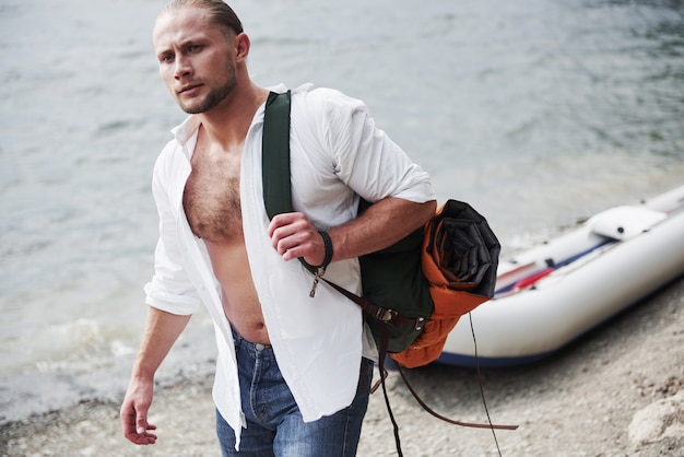 若い男がボートを使ってバックパックを持って旅行しています。旅行と自然との自然の生き方