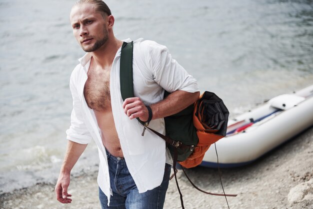 A young man is traveling with a backpack using a boat. The way of life of travel and nature with nature