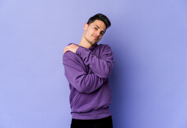 Young man isolated on purple wall hugs, smiling carefree and happy Premium Photo