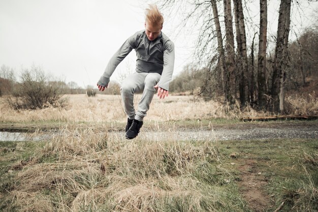 Young man jumping over the hay grass