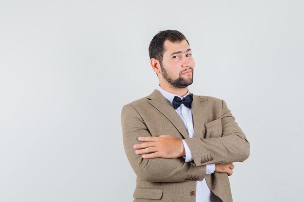 Young man keeping arms crossed in suit and looking confident. front view.