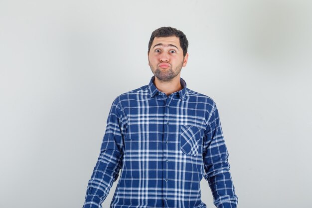 young man keeping lips folded in checked shirt