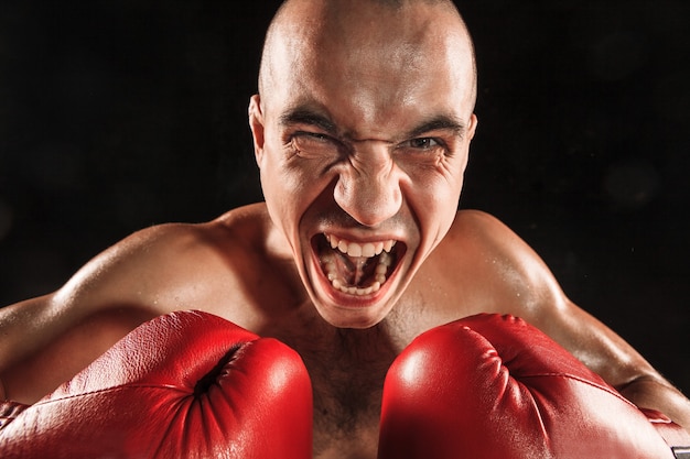 Free photo the young man kickboxing on black  with screaming face