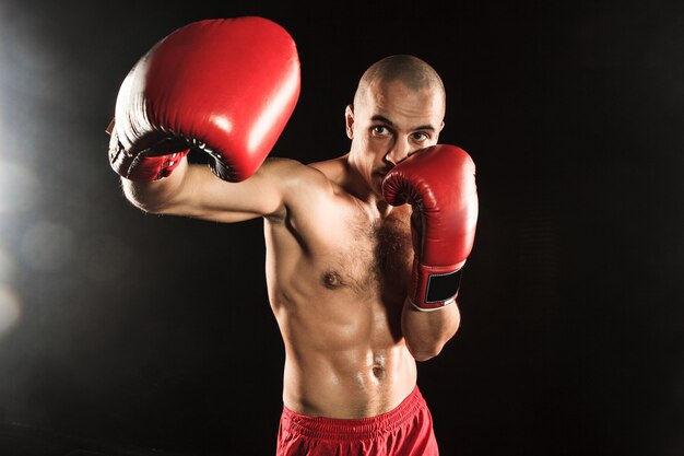 The young man kickboxing on black