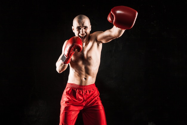 young man kickboxing on black