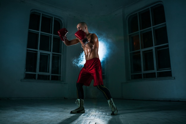 The young man kickboxing in blue smoke