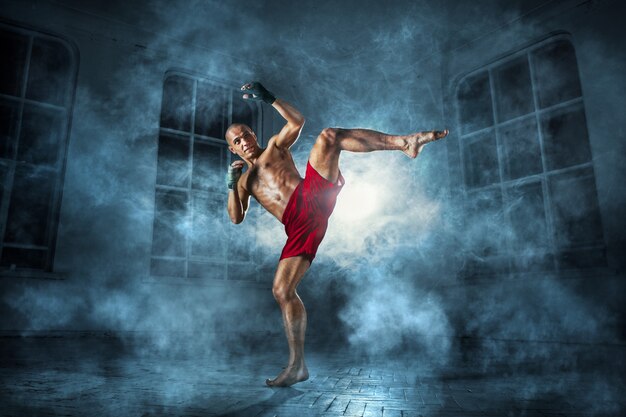 The young man kickboxing in blue smoke