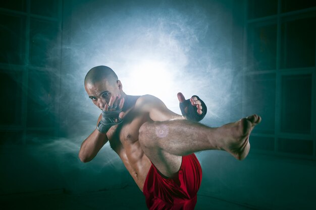 young man kickboxing in blue smoke