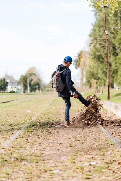  young man kicking leaves on train tracks