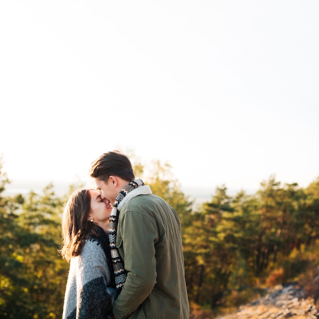 Молодой человек целует свою девушку на природе