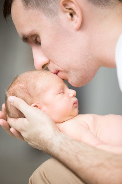 Giovane uomo bacia un neonato in palmo