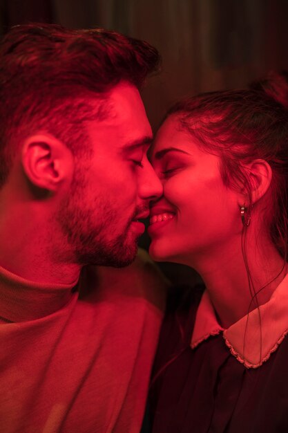Молодой человек целует улыбающуюся женщину в покраснении