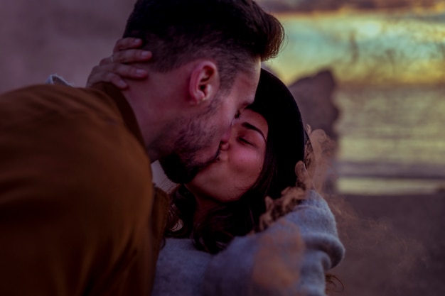 Young man kissing woman in hat