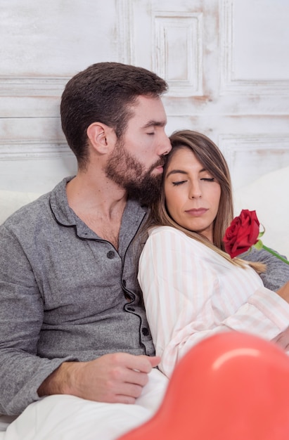무료 사진 침대에서 이마에 여자를 키스하는 젊은 남자