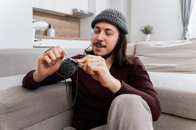 Young man knitting while relaxing