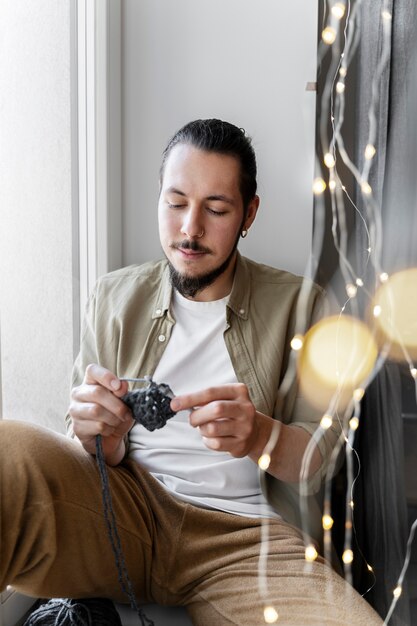 Young man knitting while relaxing
