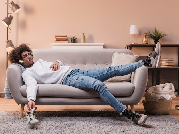 Young man laid on couch playing