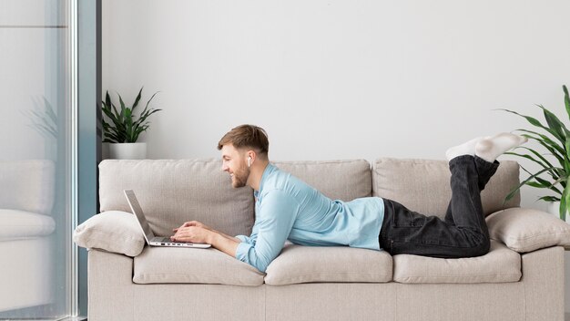 Young man laid on couch with laptop