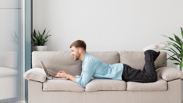 Young man laid on couch with laptop