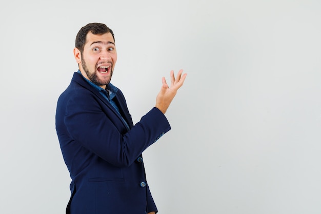 Young man laughing while raising hand in shirt, jacket.