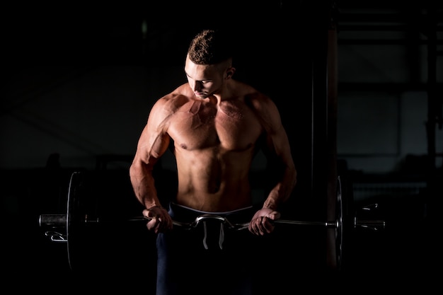 Young man lifting a barbell in gym