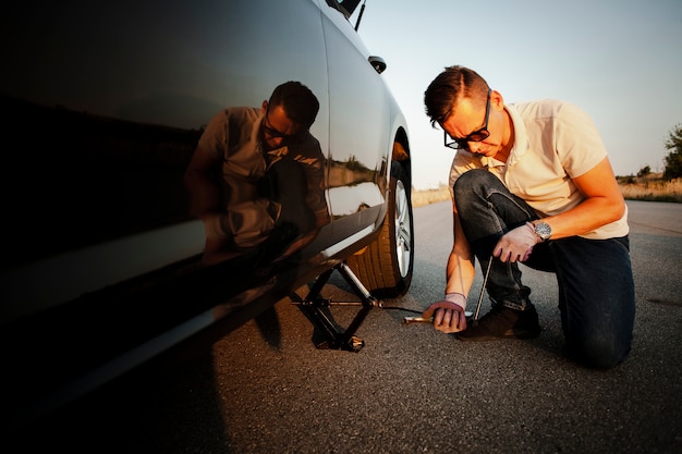 Young man lifting up the car with