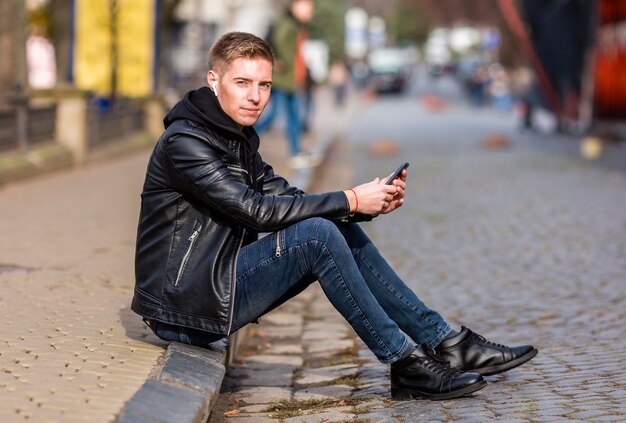 Young man listening to music on earbuds outside