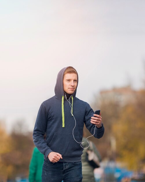 Young man listening to music on earphones while jogging