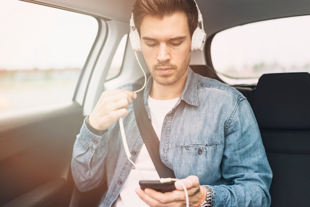 Young man listening music on headphone while travelling in the car