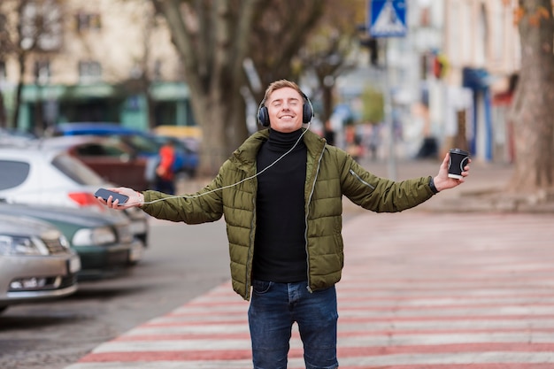 Free photo young man listening to music on headphones on the streets