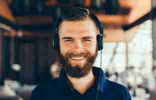 Free photo young man listening music in headphones, using smartphone, outdoor hipster portrait