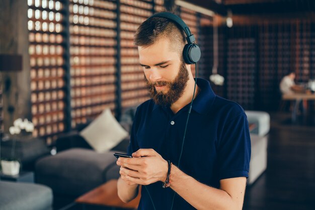 젊은이 스마트 폰, 야외 hipster 초상화를 사용 하여 헤드폰에서 음악 듣기