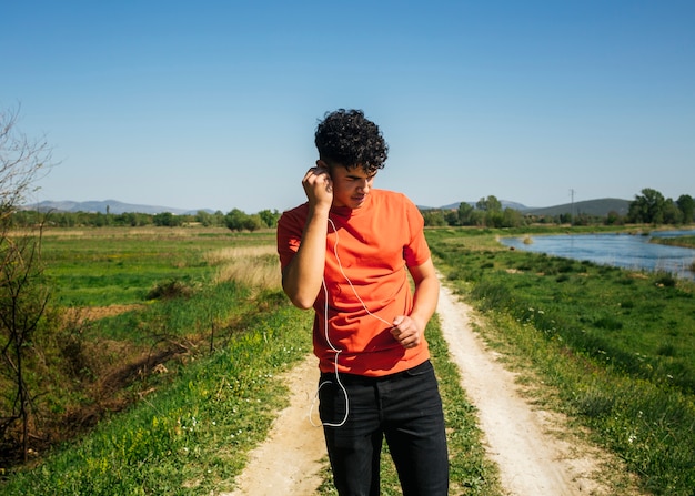 Young man listening music while walking on natural trail