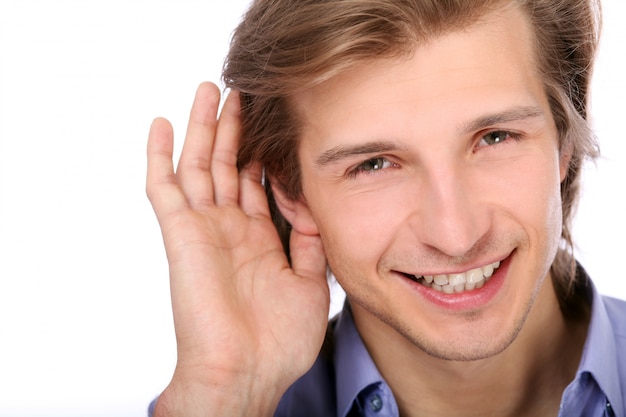 Молодой человек слушает с рукой на ухе