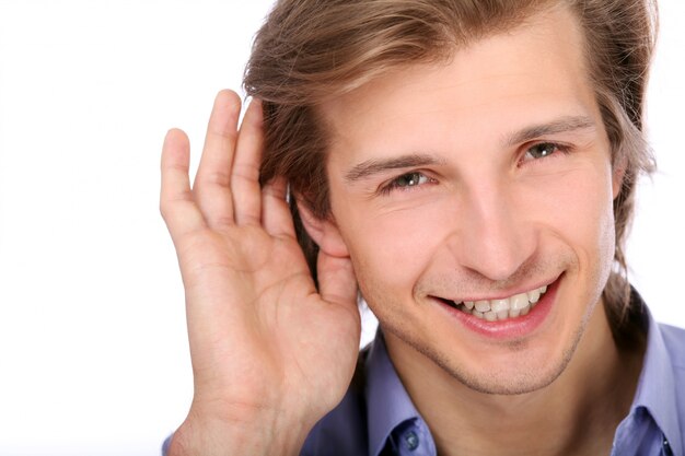 Young man listening with hand on ear