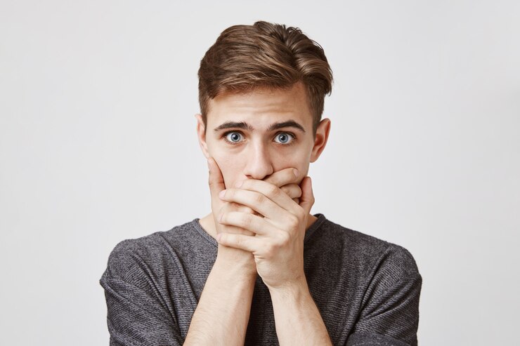 Free Photo young man looking afraid, covering his mouth