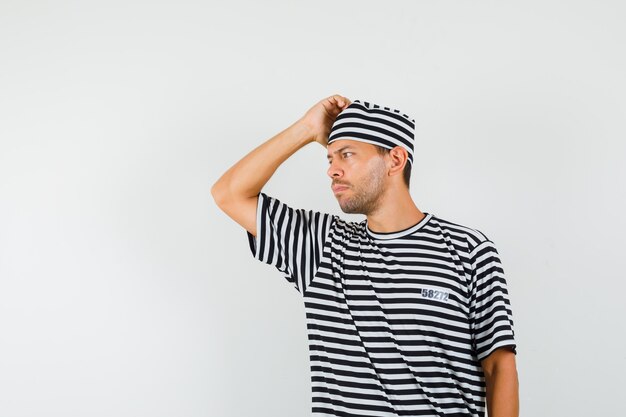 Young man looking aside in striped t-shirt hat and looking thoughtful