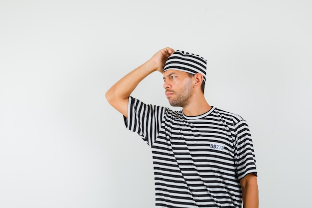 Young man looking aside in striped t-shirt hat and looking thoughtful