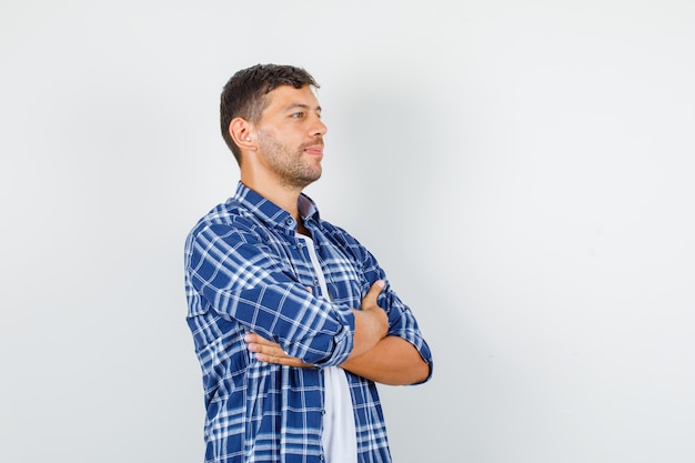 Young man looking away crossed arms in shirt and looking hopeful. front view.