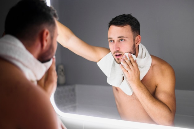 Young man looking in the bathroom mirror