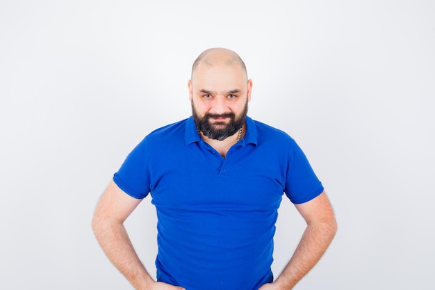 Young man looking at camera in blue shirt and looking concentrated. front view.