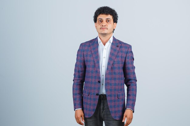 Young man looking at camera in shirt, jacket, pants and looking handsome , front view.