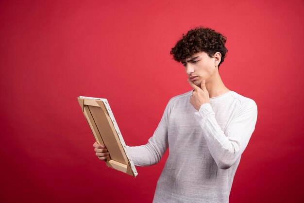 Young man looking at empty canvas with thoughtful gaze.