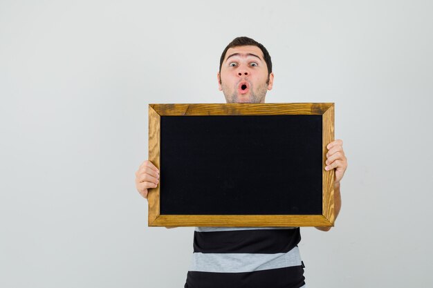 Young man looking over frame in t-shirt and looking excited