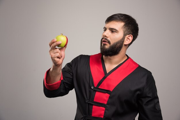 Young man looking on a fresh apple .