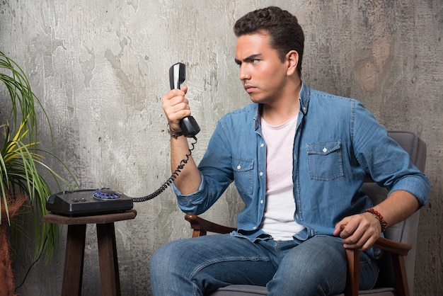 Young man looking on handset and sitting on chair. High quality photo