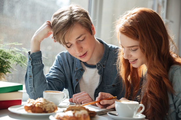 Young man looking at his young womanfriend doing homework