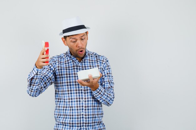 Young man looking into gift box in checked shirt